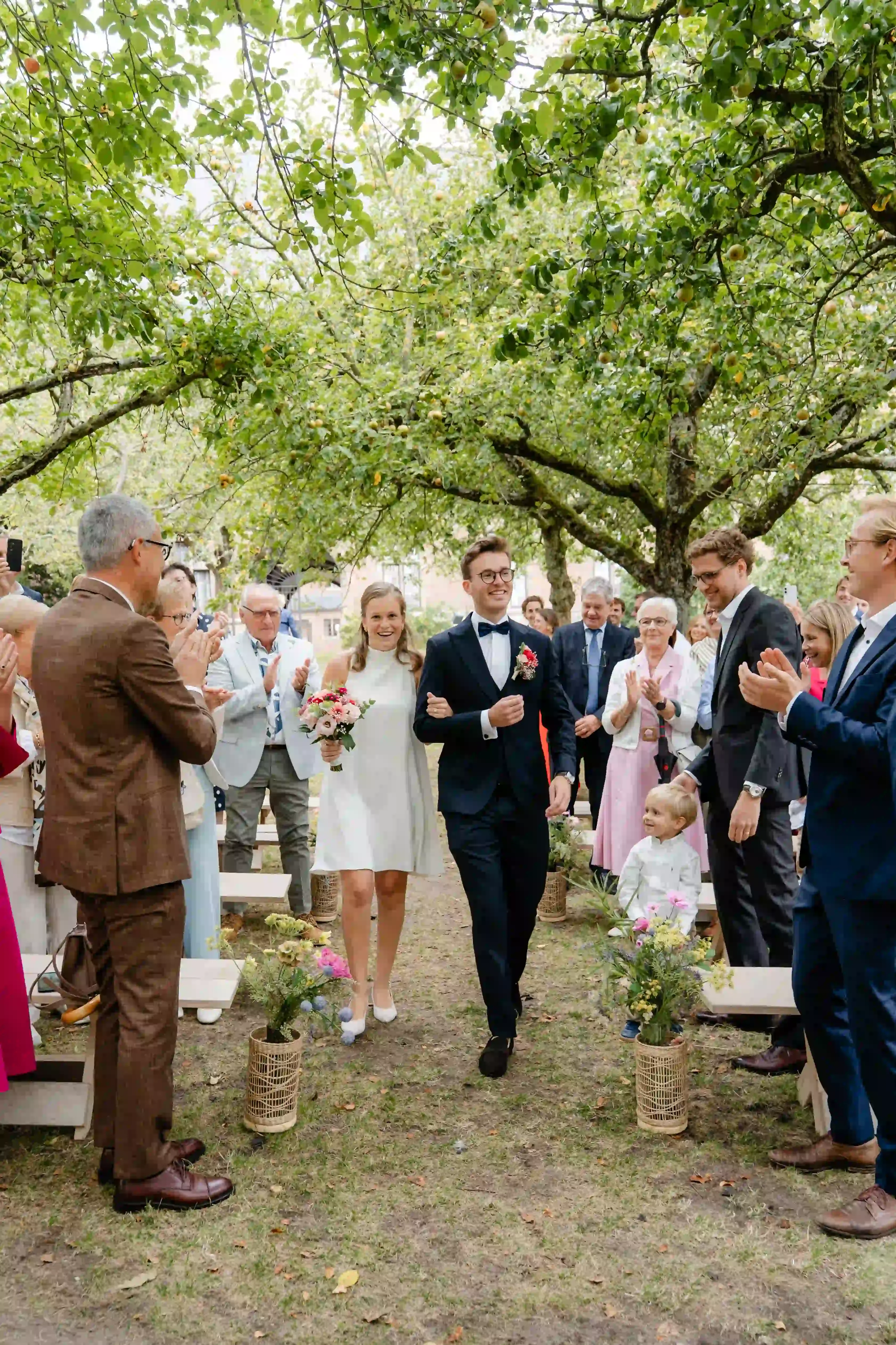 Wedding photography by Bert Van Den Eeckhaut — bride groom and guests gathered in an outdoor setting under a tree