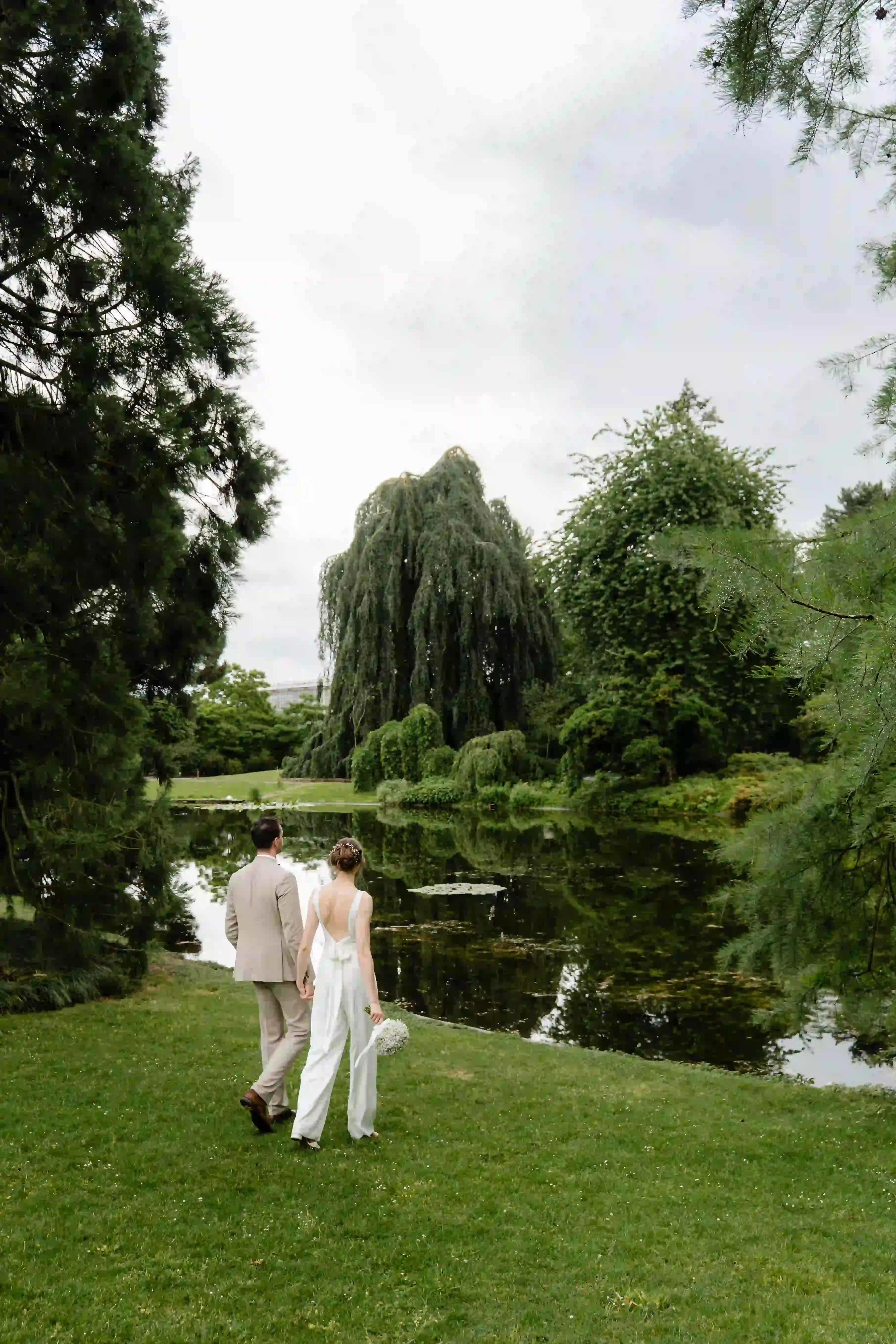 Wedding photography by Bert Van Den Eeckhaut — bride and groom at park, overlooking pond, with weeping willow tree in background