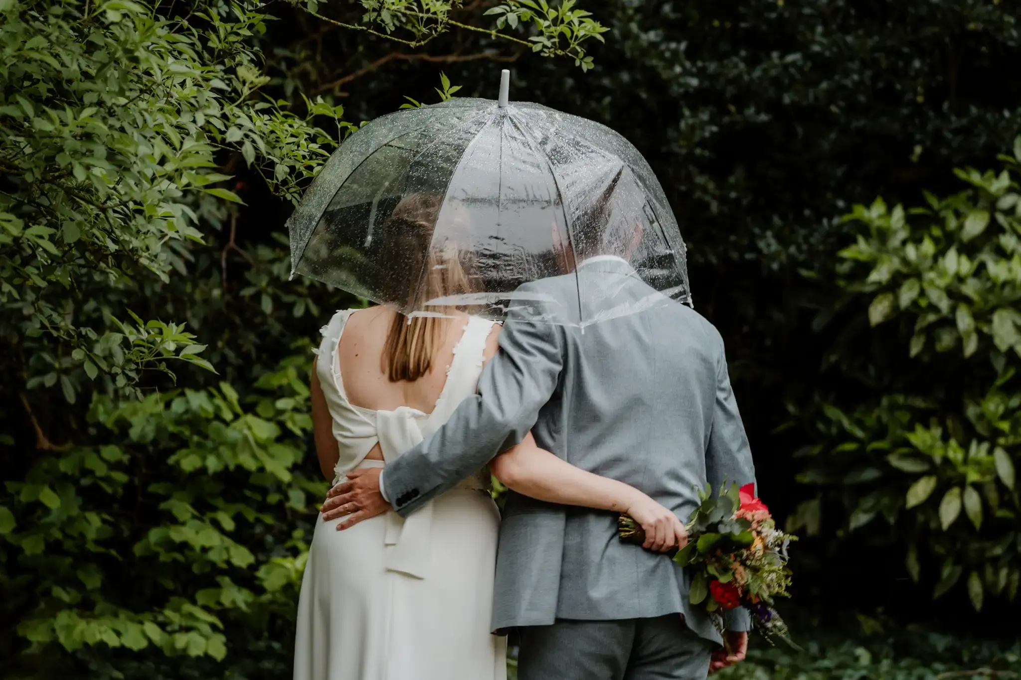 Wedding photography by Bert Van Den Eeckhaut — groom and bride sharing umbrella during rain