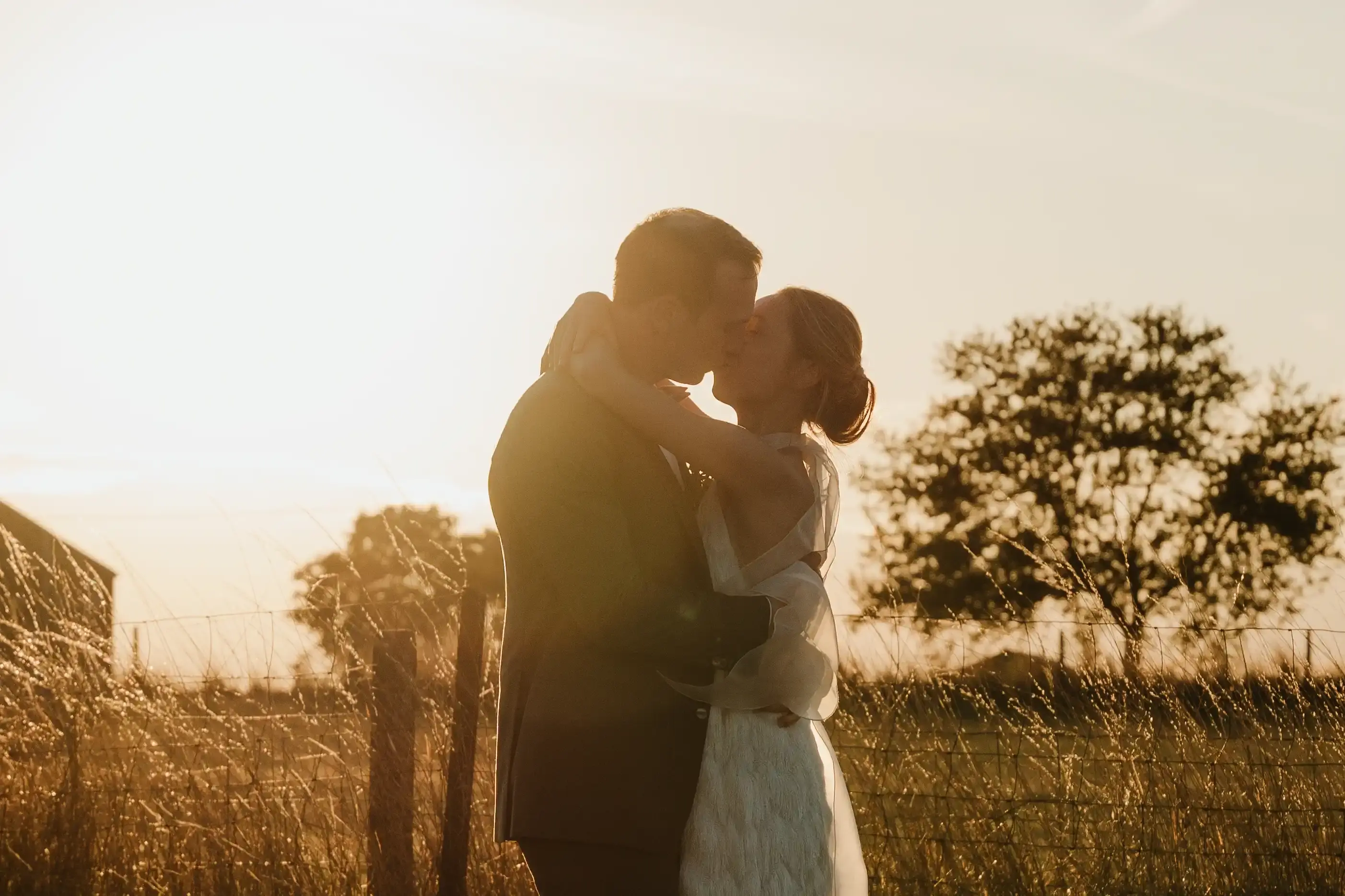 Wedding photography by Bert Van Den Eeckhaut — romantic couple kissing at sunset in field