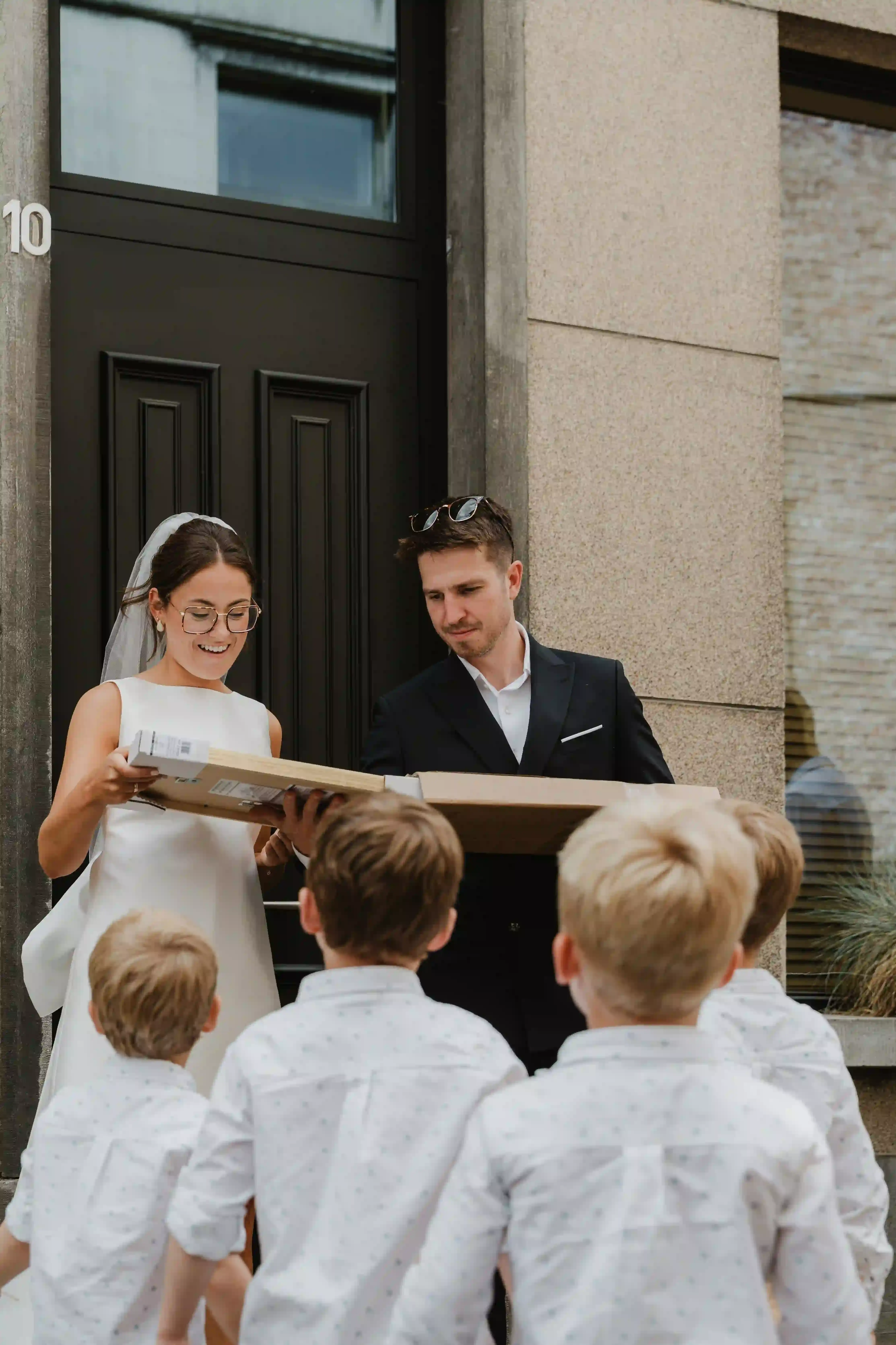 Wedding photography by Bert Van Den Eeckhaut — bride and groom present gifts to young boys waiting outside