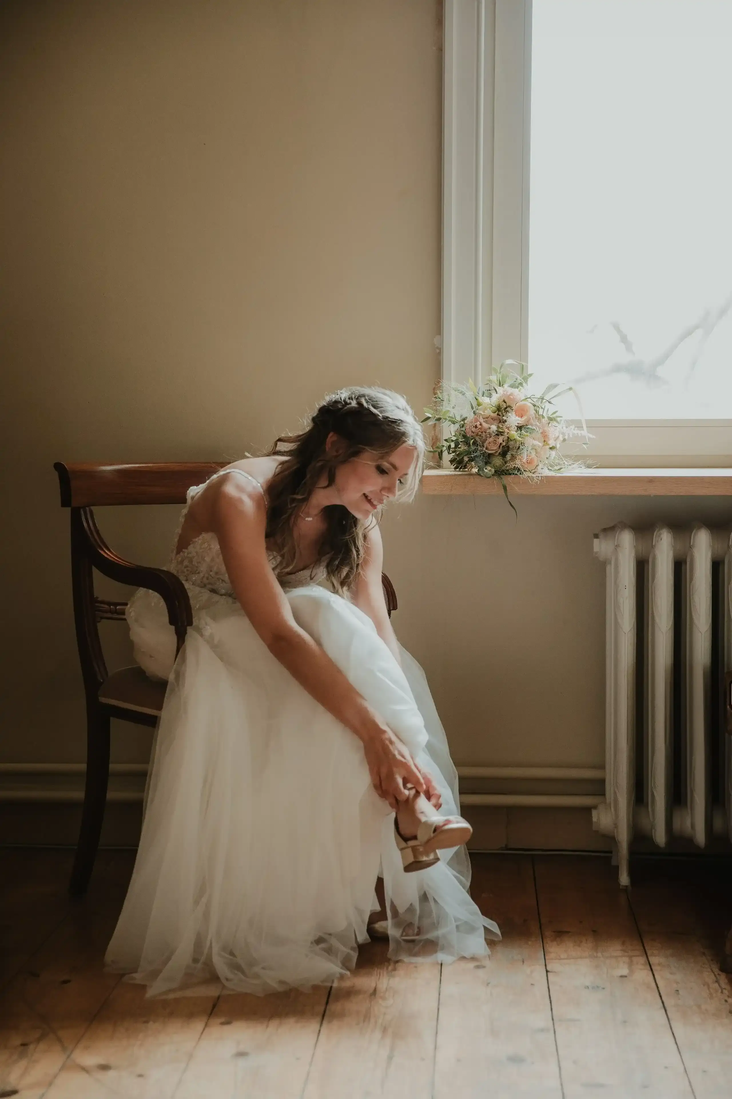 Wedding photography by Bert Van Den Eeckhaut — bride sitting down shoe in hand